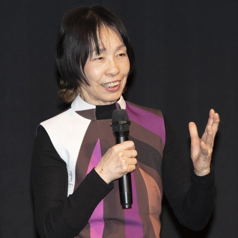 マイクを持って笑顔で話す女性