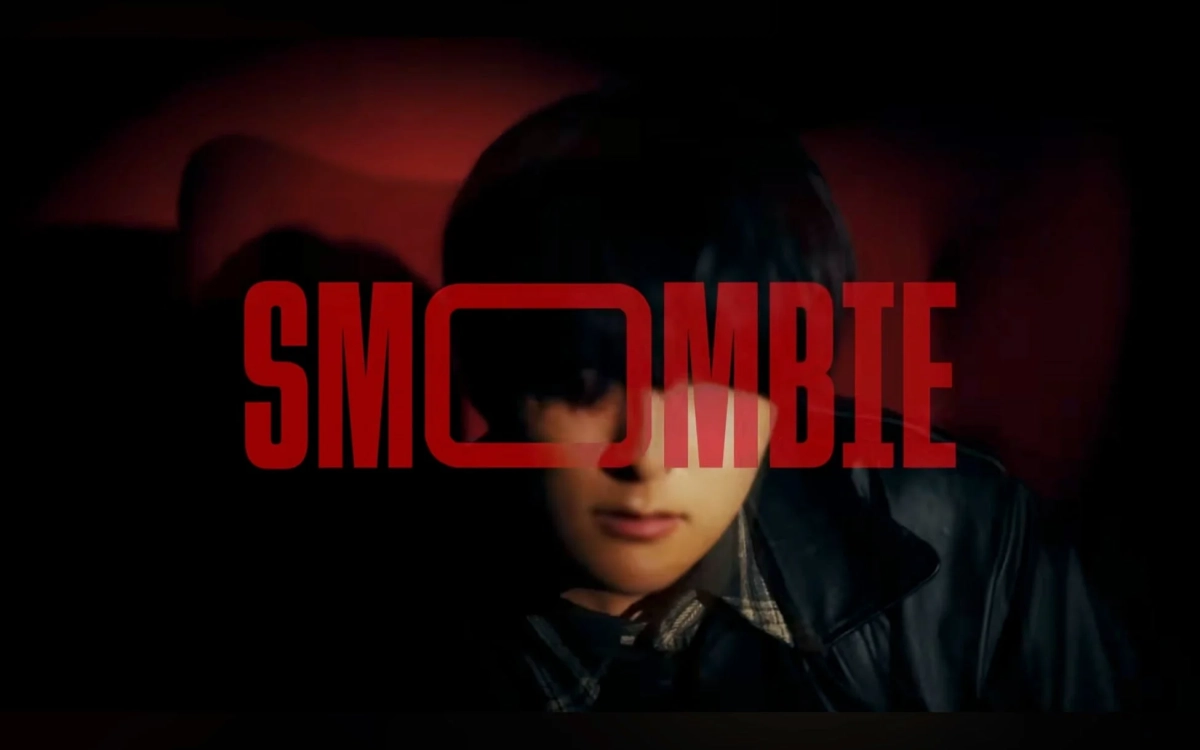 暗闇の中、赤文字で「SMOMBIE」と書かれたタイトルロゴが、顔の一部を隠すように配置された若者の顔を捉えています。