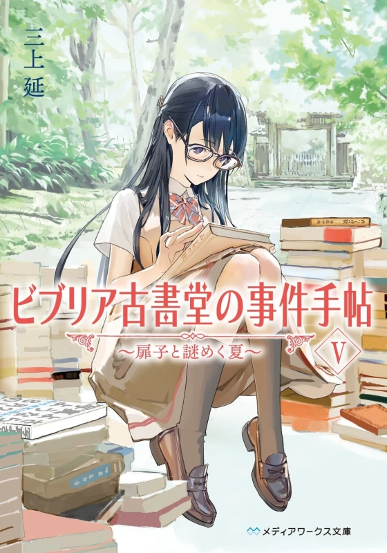 緑豊かな自然の中で、眼鏡をかけた制服姿の少女が古書に囲まれながら本を読んでいるイラスト。ライトノベル「ビブリア古書堂の事件手帖」の表紙で、夏をテーマにした物語の雰囲気を表しています。