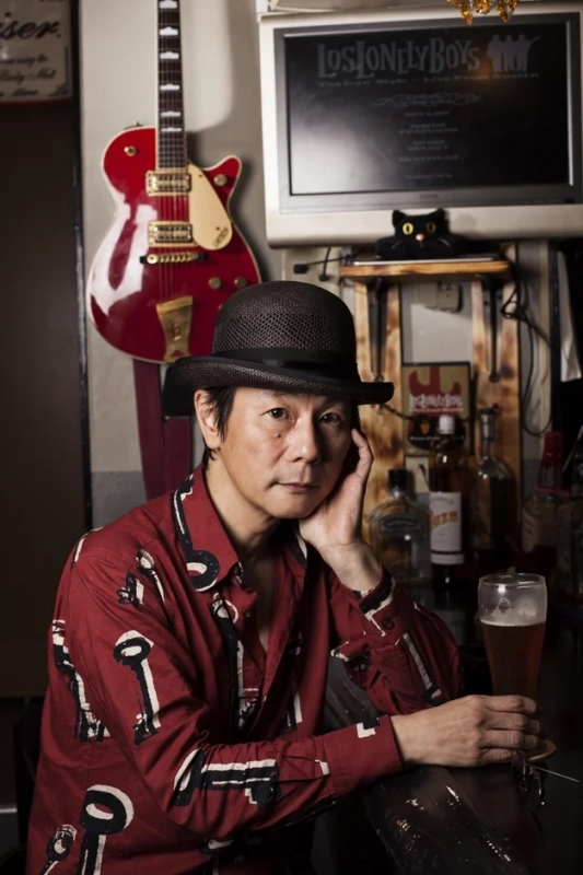 帽子をかぶった男性がバーカウンターでビールを片手にリラックスしている様子